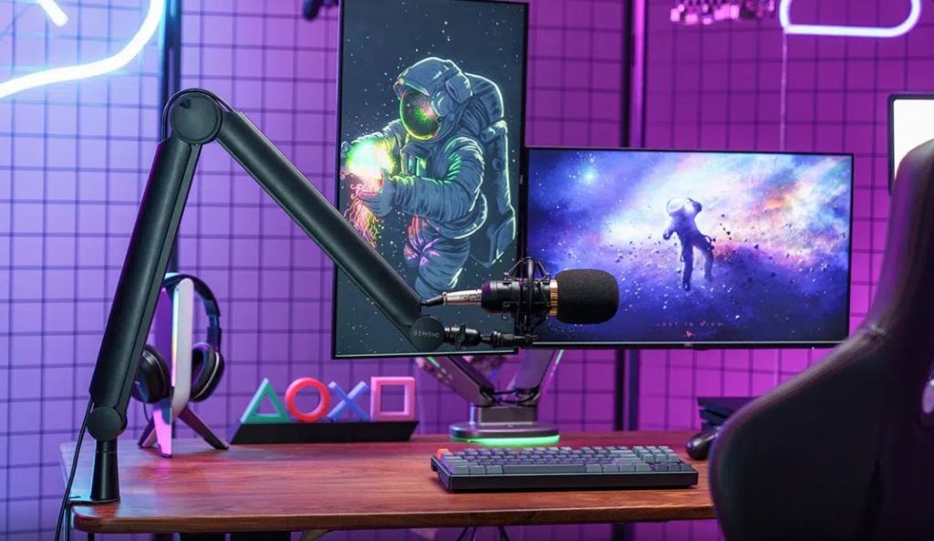 Streaming desk setup with condenser mic on boom arm, dual monitors, and purple neon lighting