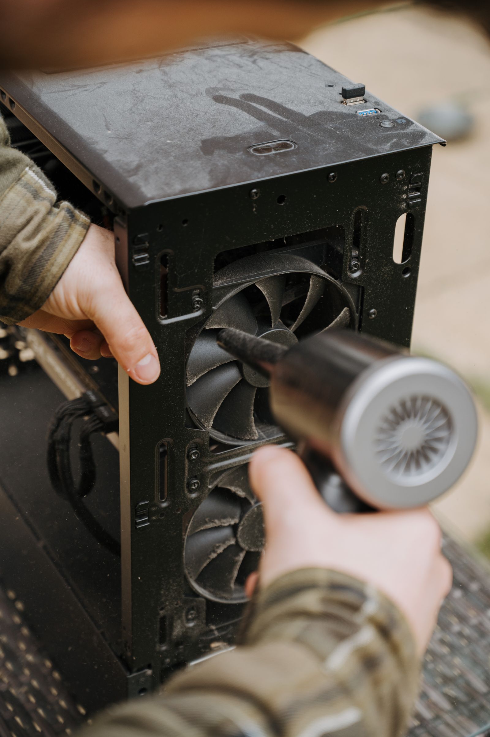 Person using an air duster to clean a computer fan