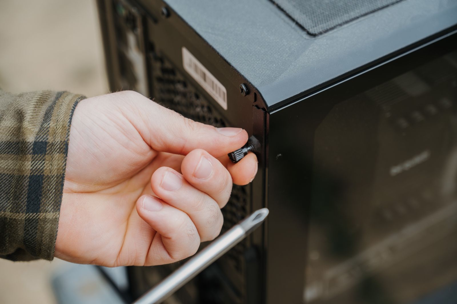 Hand unscrewing a desktop computer case