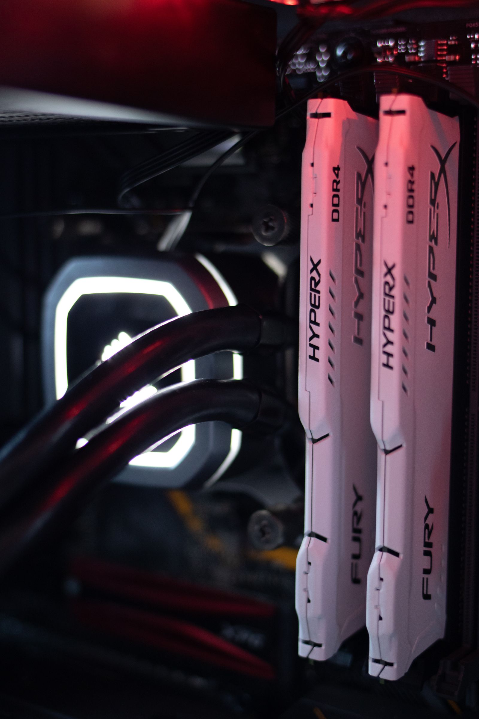 Two RAM sticks installed in a motherboard with liquid cooling nearby