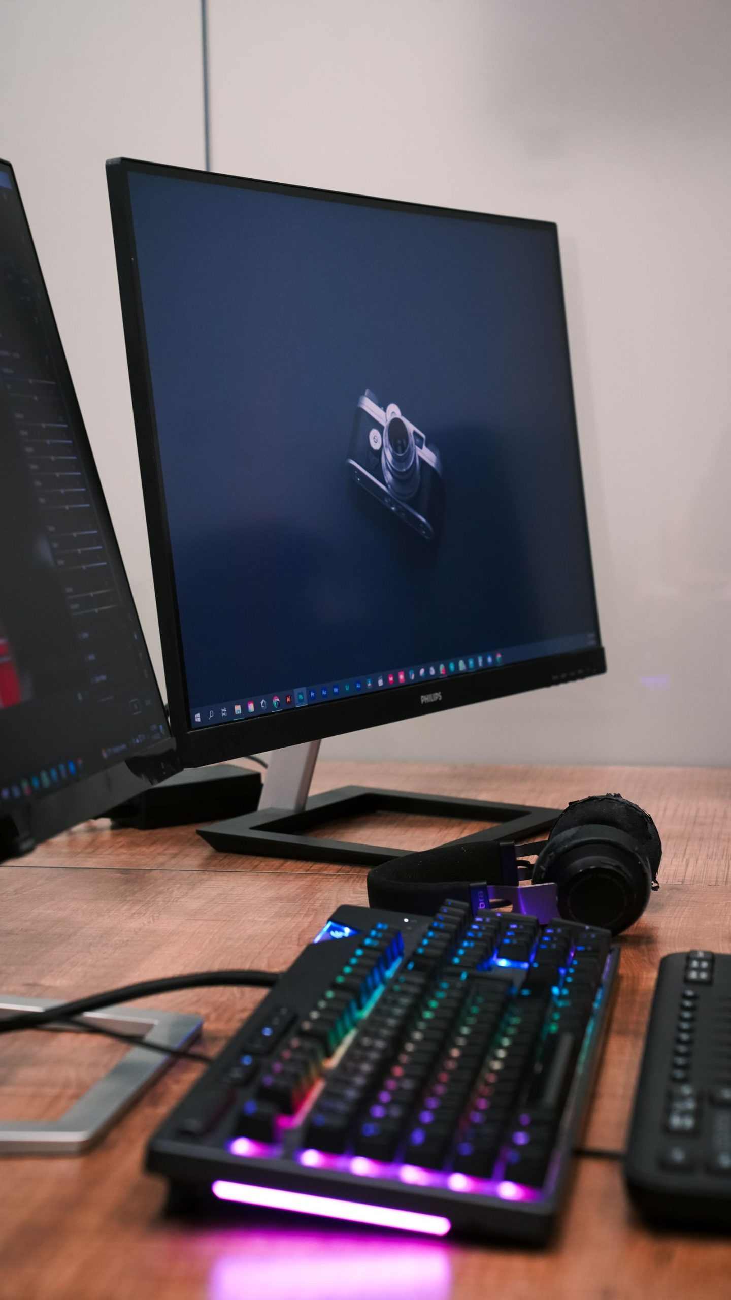 Dual monitor desk setup with RGB keyboard and headphones
