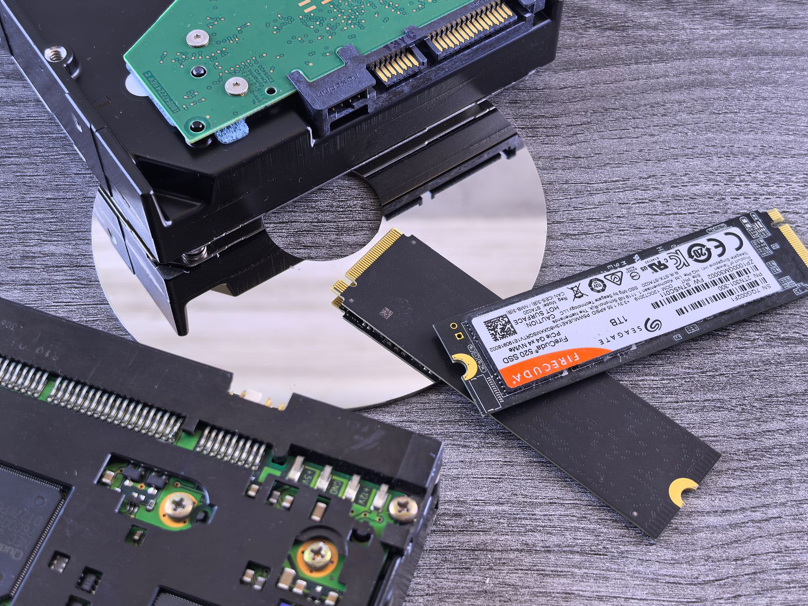 NVMe SSD next to a traditional hard drive and CD, comparing storage technologies