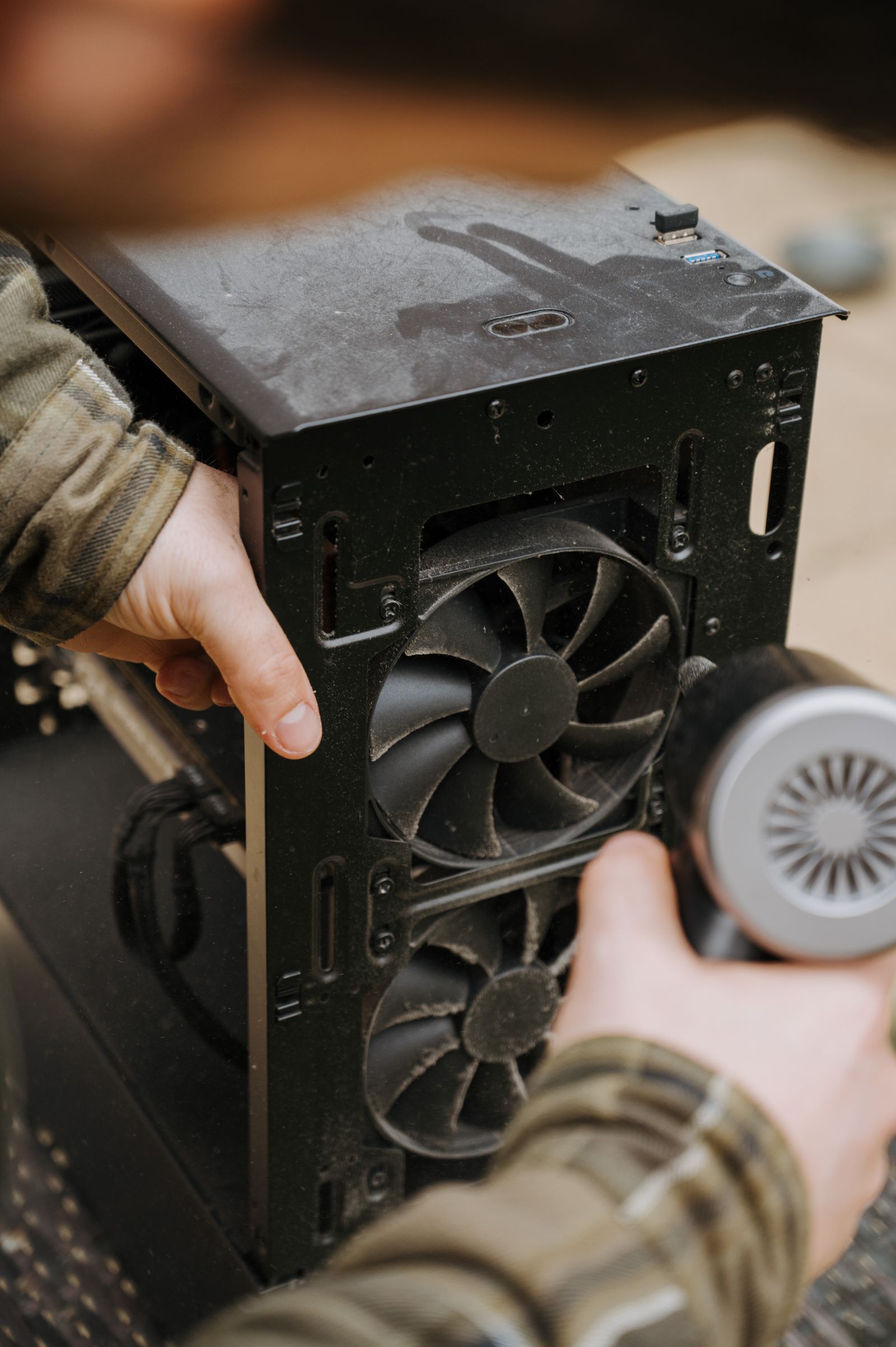 Hands cleaning dust from a computer cooling fan